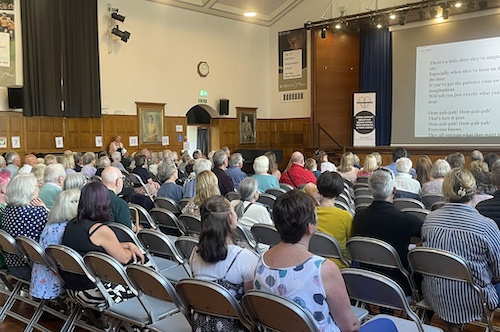 Photograph of 'The Big Sing' in a large hall with many people