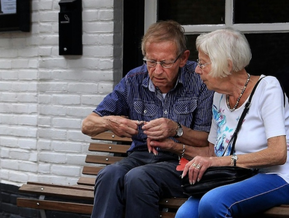 Older couple sitting on bench looking at a phone together
