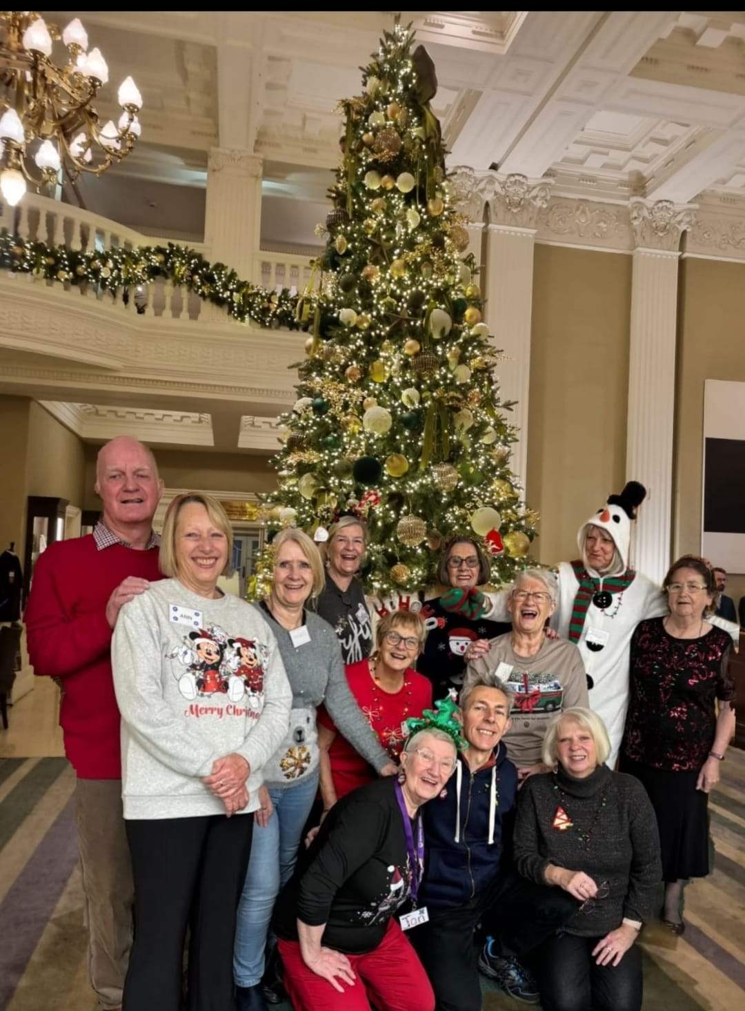 Photo of the voulenteers gathered around a Christmas tree, some wearing fancy dress